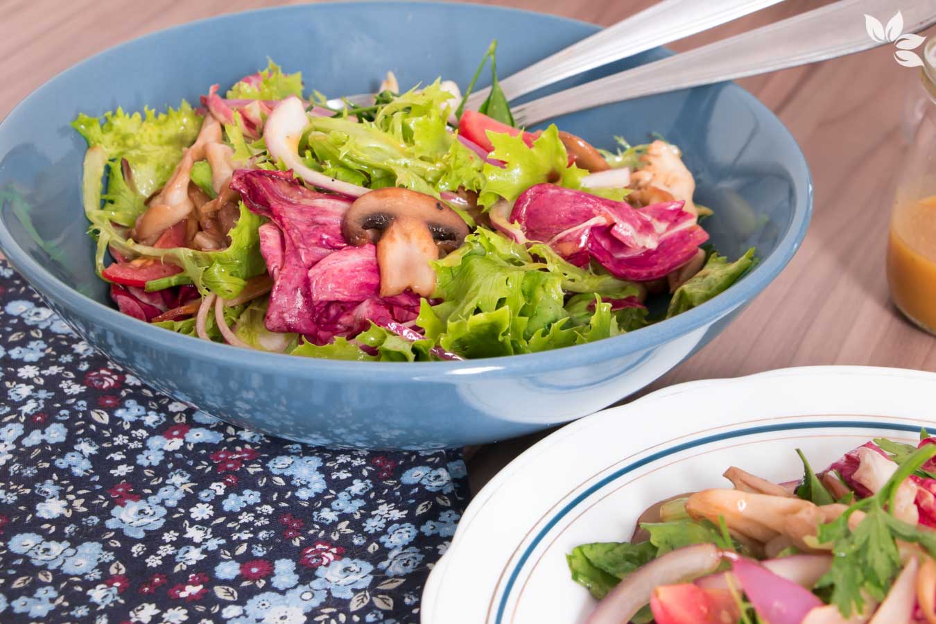 Salada de folhas verdes com cogumelos caramelizados, servida em um prato fundo azul.