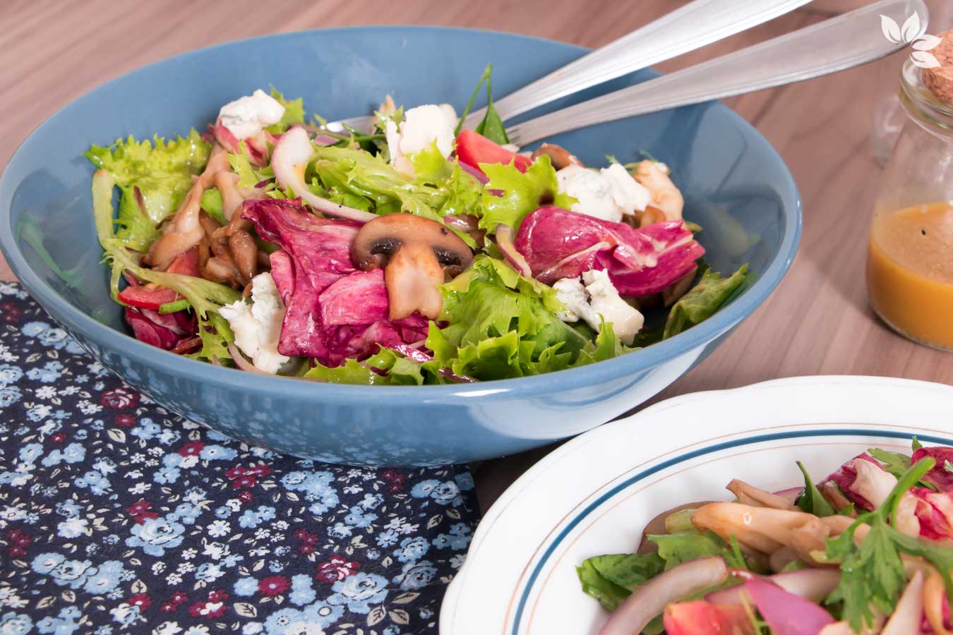 Salada de folhas verdes com cogumelos caramelizados, servida em um prato fundo azul.